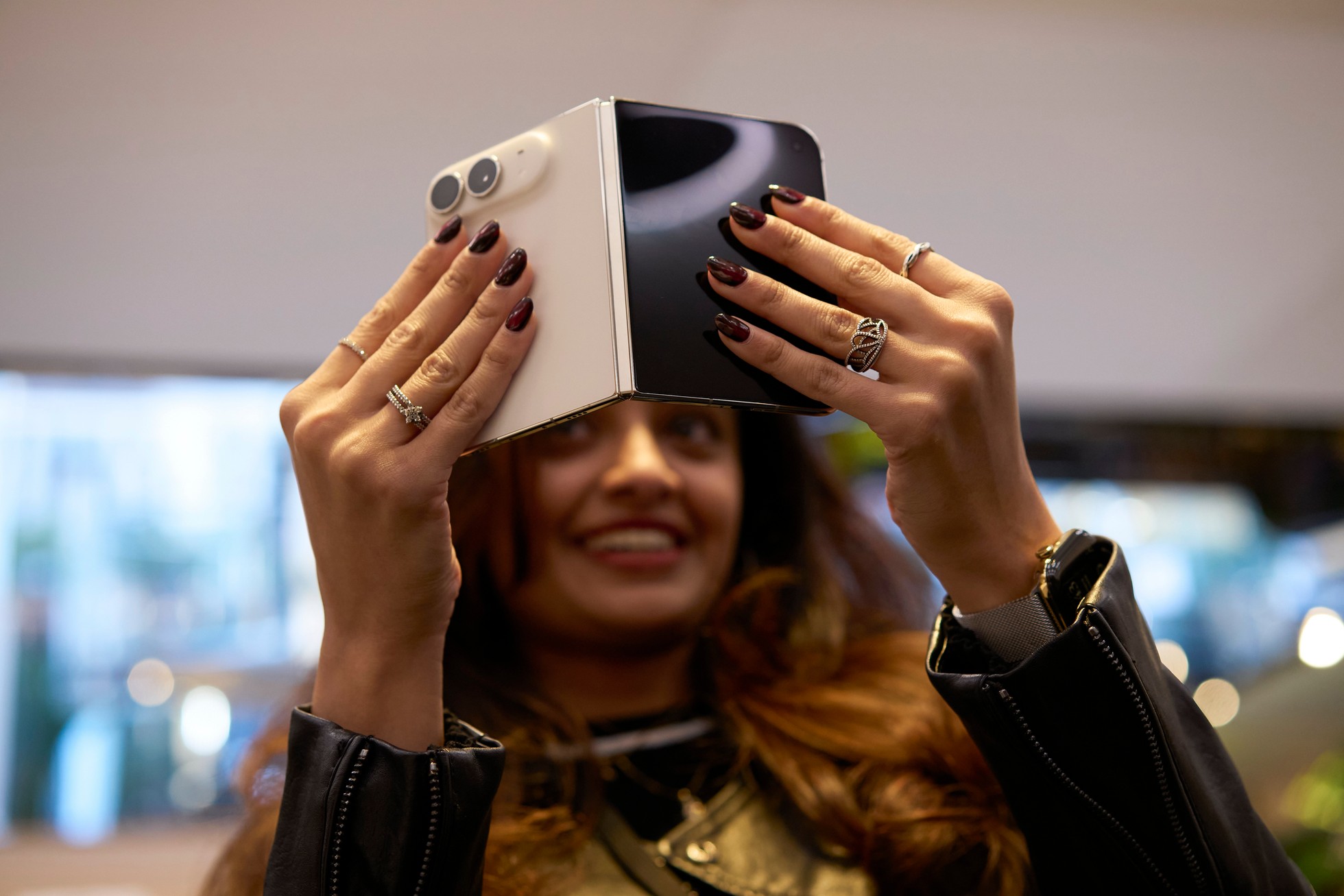 A customer at Apple Fifth Avenue holds up a partially folded star white iPhone Duo with both hands